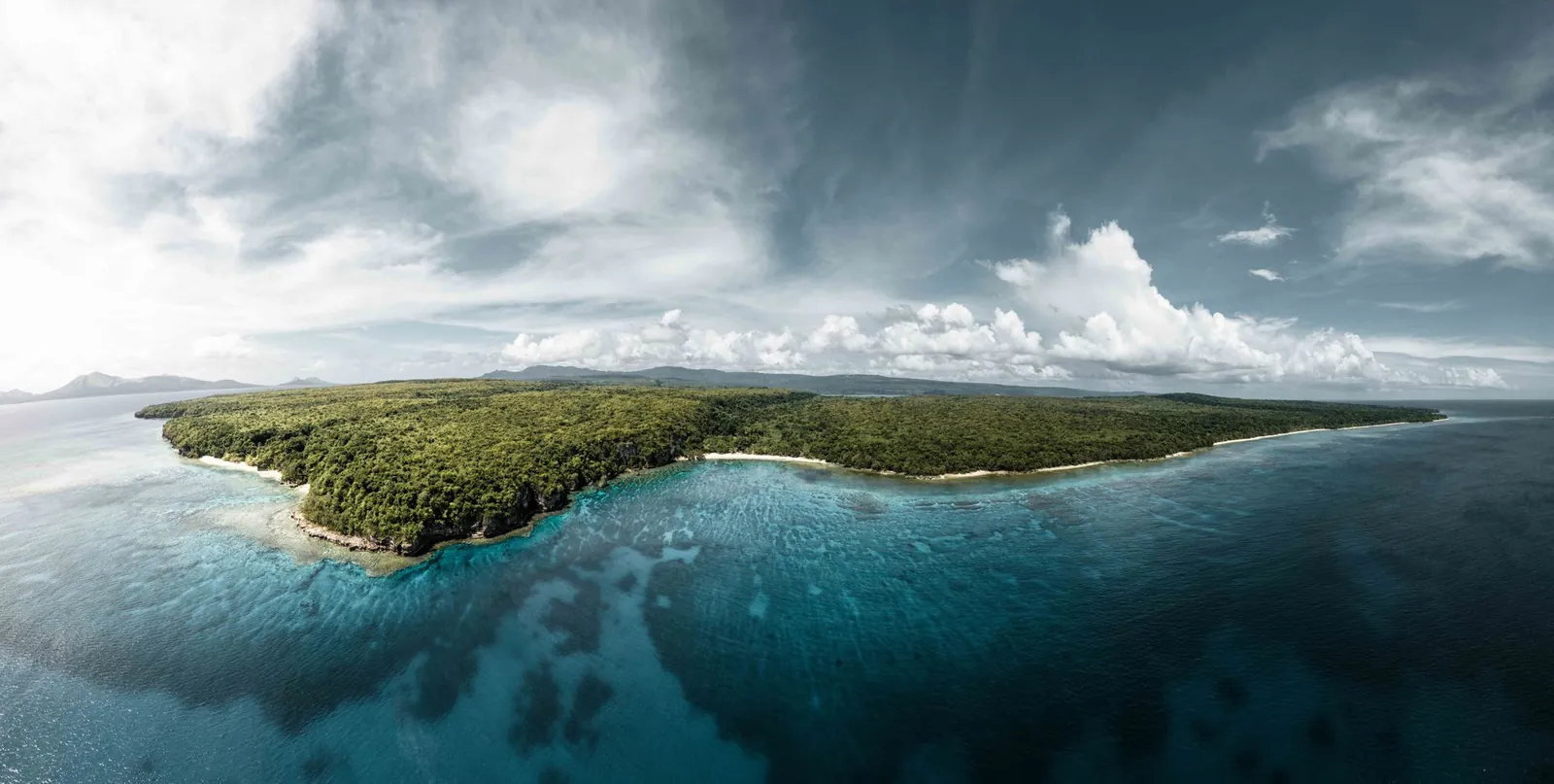 Aerial view of a green island and coral reefs off the coast of Vanuatu